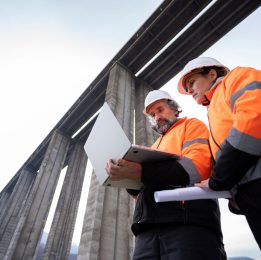 a man and a woman in construction gear reviewing a laptop